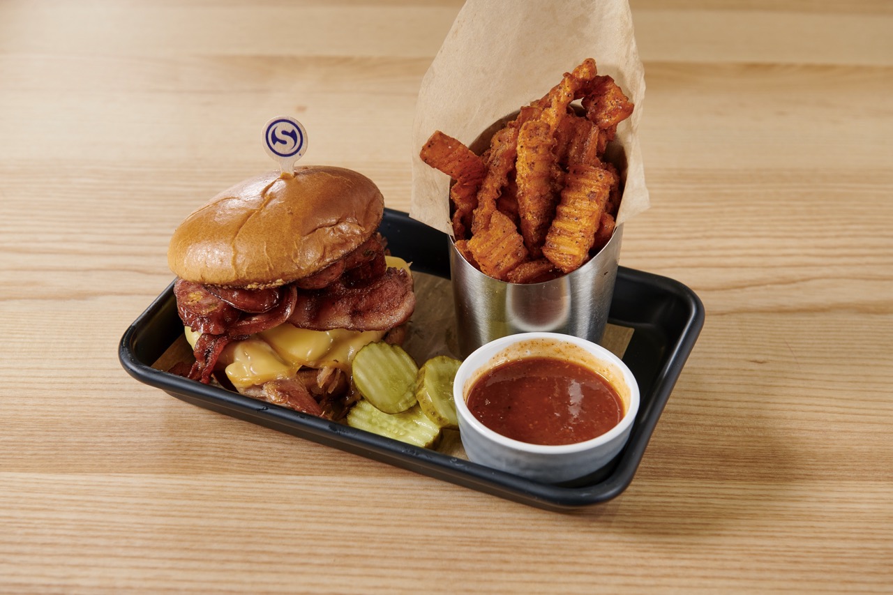 cheeseburger with fries, pickles and ketchup on a tray.