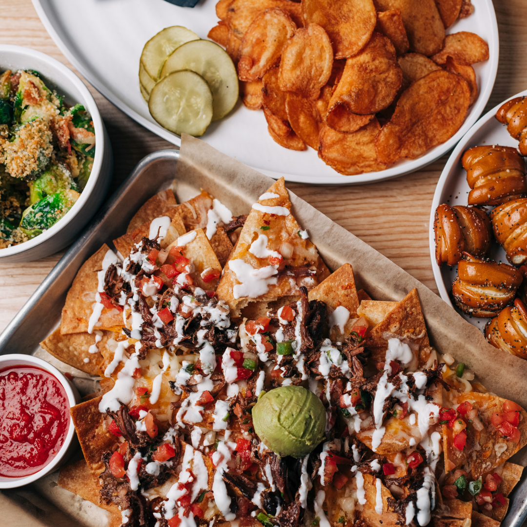 Loaded shredded-beef nachos with guacamole and pico, alongside kettle chips, crispy brussels sprouts and pretzel bites